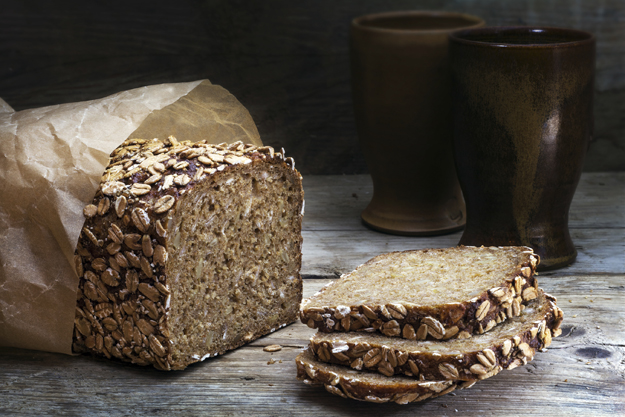 wholegrain bread with seeds on weathered wood, dark background