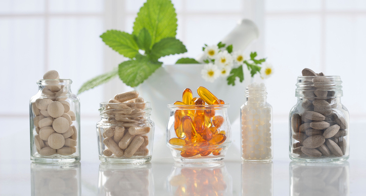 Herbal medicine pills and mortar over bright  background